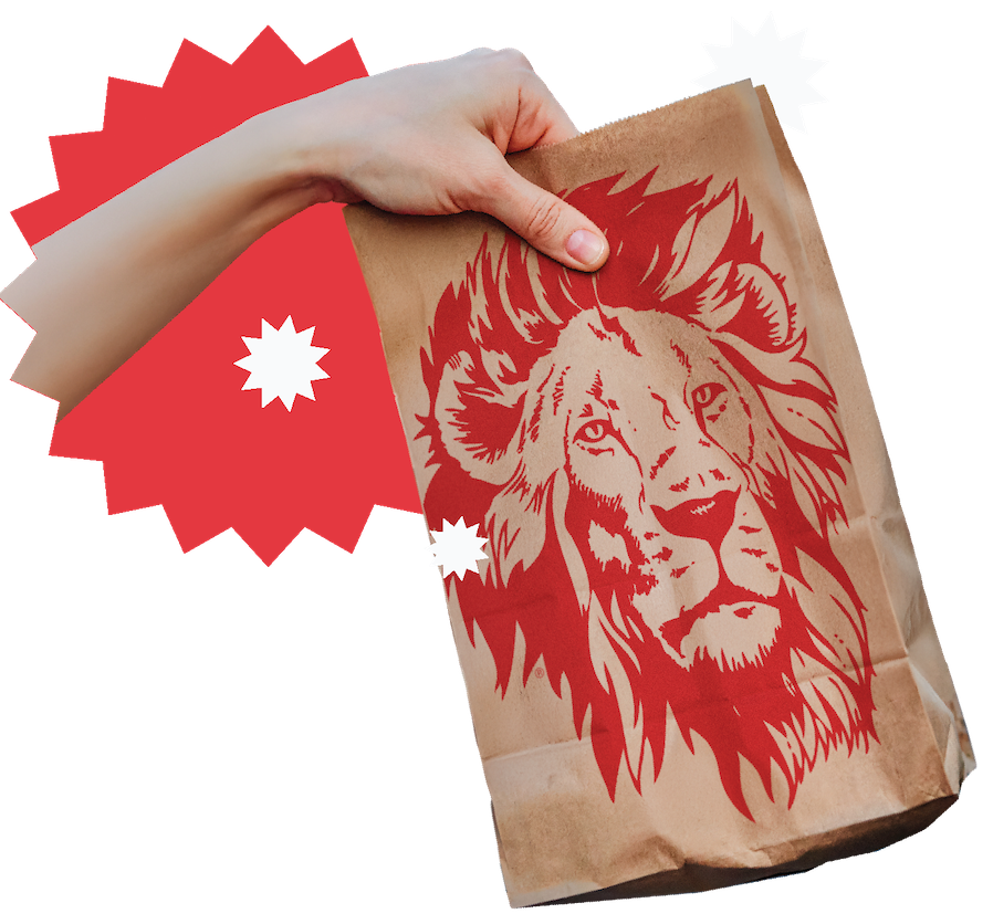 A hand holding a paper bag with a red lion on it
